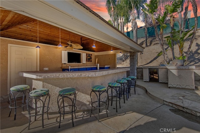 patio terrace at dusk featuring a wet bar and ceiling fan