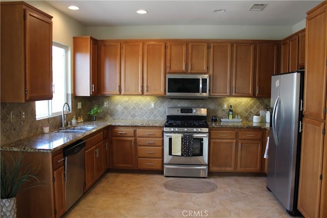 kitchen with light stone countertops, stainless steel appliances, decorative backsplash, light tile patterned flooring, and sink