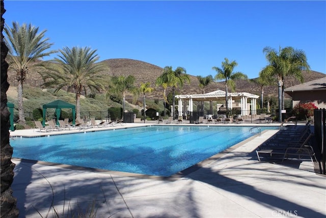 view of swimming pool featuring a patio, a pergola, a mountain view, and a gazebo