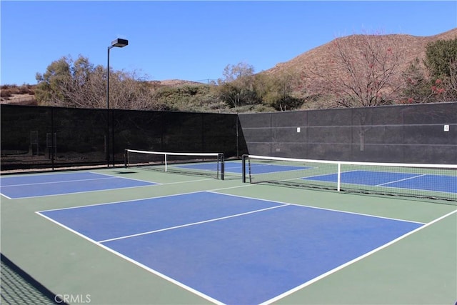 view of tennis court with a mountain view and basketball hoop