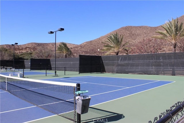 view of tennis court with basketball hoop and a mountain view