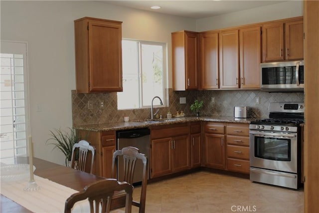 kitchen featuring appliances with stainless steel finishes, tasteful backsplash, dark stone countertops, and sink