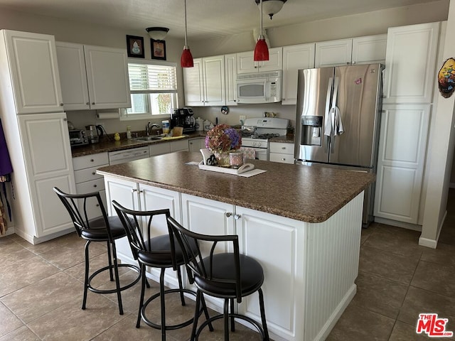 kitchen with white appliances, white cabinetry, and a kitchen island