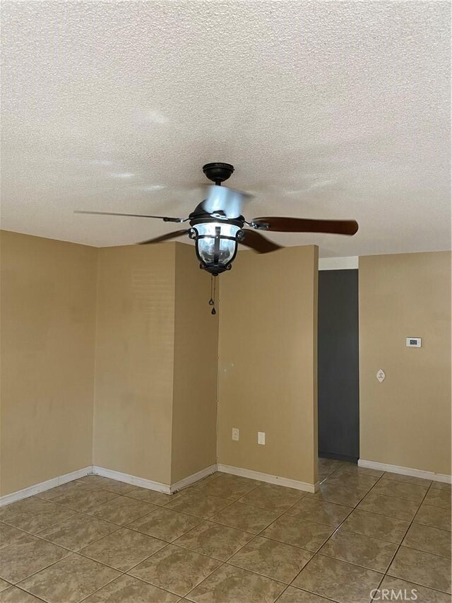 empty room featuring ceiling fan, tile patterned flooring, and a textured ceiling