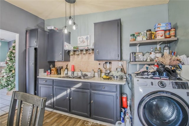 interior space featuring washer / dryer, laundry area, light wood finished floors, a sink, and indoor wet bar