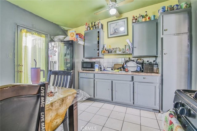 kitchen with light tile patterned floors, ceiling fan, appliances with stainless steel finishes, light countertops, and gray cabinetry