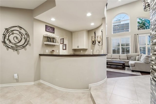 kitchen featuring open floor plan, light tile patterned floors, dark countertops, and white cabinetry