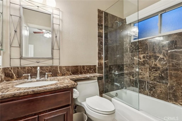 full bathroom with vanity, decorative backsplash, shower / bath combination with glass door, and toilet