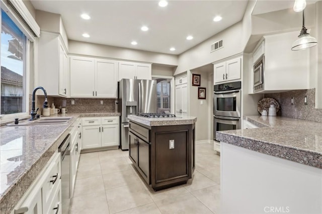 kitchen featuring appliances with stainless steel finishes, light countertops, a sink, and decorative light fixtures