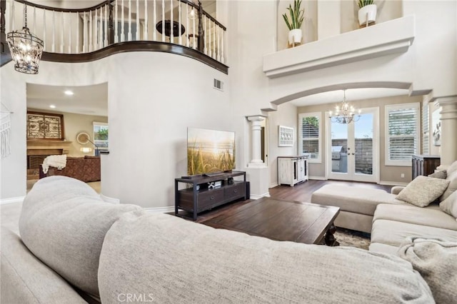 living room featuring arched walkways, a towering ceiling, visible vents, baseboards, and french doors