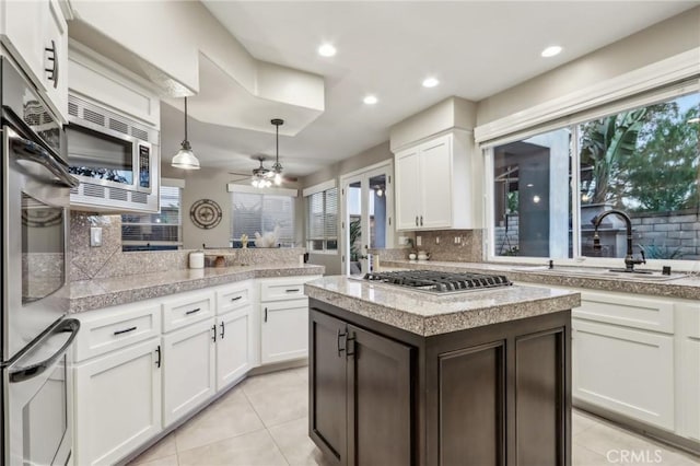 kitchen featuring stainless steel appliances, white cabinets, light countertops, and a sink