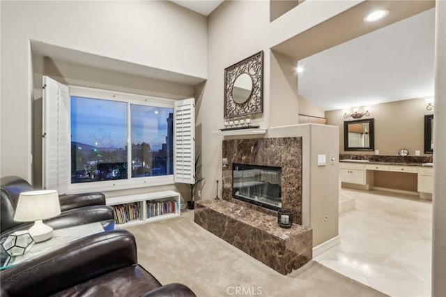 carpeted living room with a high ceiling and a premium fireplace