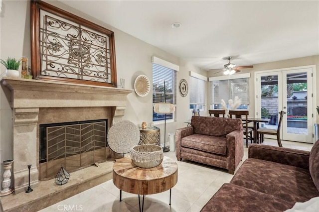 tiled living room with ceiling fan, a high end fireplace, and french doors