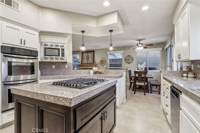 kitchen featuring white cabinets, stainless steel appliances, a kitchen island, and light countertops