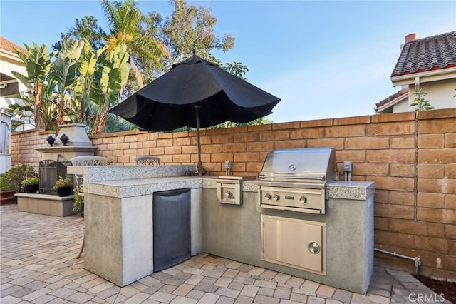 view of patio with grilling area, fence, and an outdoor kitchen