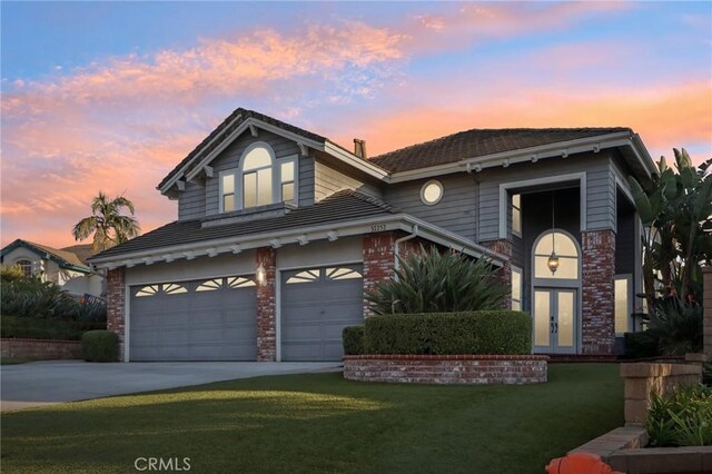 front of property with a lawn, french doors, and a garage