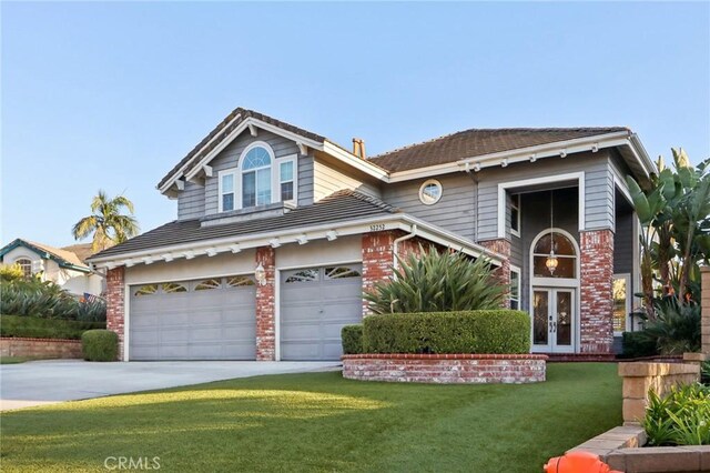 front of property featuring a garage, a front yard, and french doors