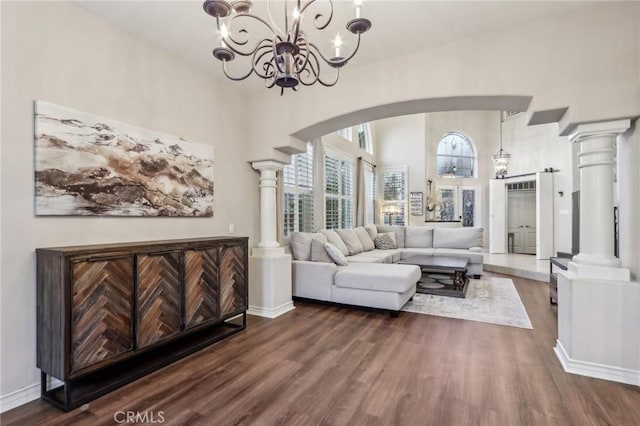 living room featuring dark wood-type flooring, a towering ceiling, and decorative columns