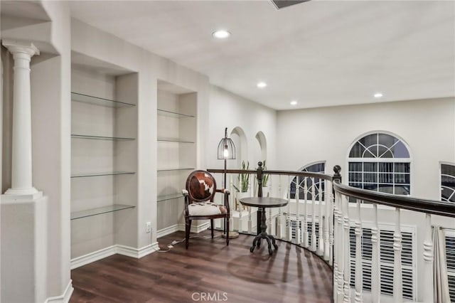 hallway with built in features, baseboards, dark wood finished floors, and ornate columns