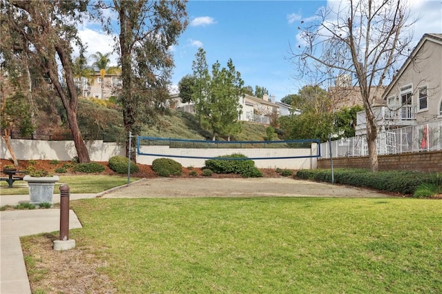 view of community with a yard, fence, and volleyball court