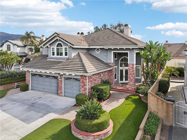 view of front of home featuring an attached garage, driveway, a tile roof, and brick siding