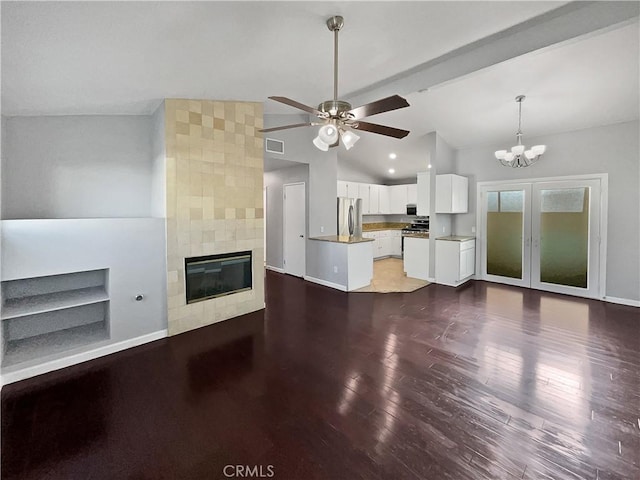 unfurnished living room with vaulted ceiling, dark hardwood / wood-style floors, ceiling fan with notable chandelier, and a tiled fireplace