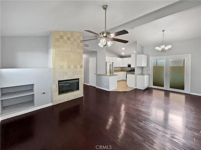 unfurnished living room featuring french doors, vaulted ceiling, dark hardwood / wood-style flooring, a fireplace, and ceiling fan with notable chandelier