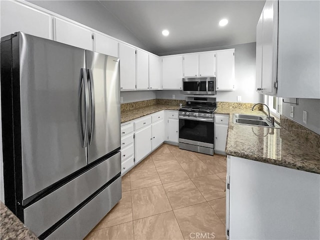 kitchen with white cabinetry, appliances with stainless steel finishes, dark stone countertops, vaulted ceiling, and sink