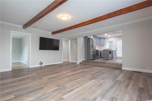 unfurnished living room featuring wood-type flooring, sink, and crown molding