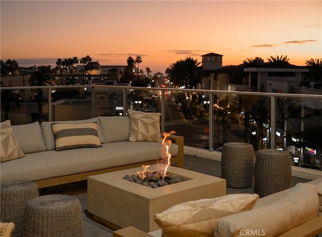 patio terrace at dusk featuring a balcony and an outdoor living space with a fire pit