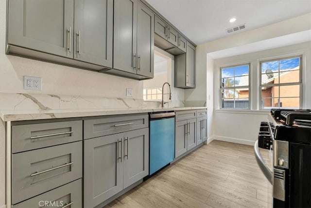 kitchen with light stone countertops, sink, gray cabinets, and stainless steel appliances