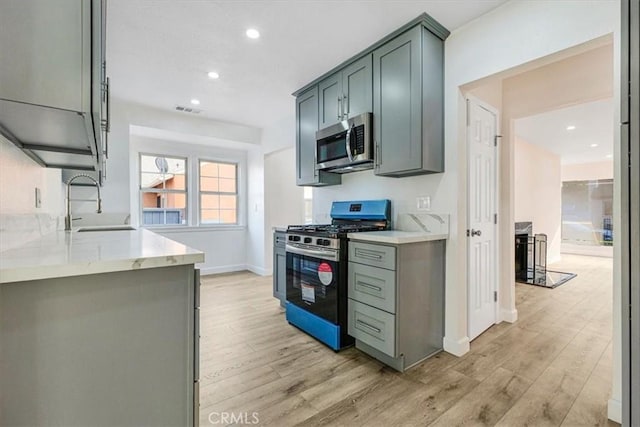 kitchen featuring light stone countertops, sink, stainless steel appliances, and light hardwood / wood-style floors