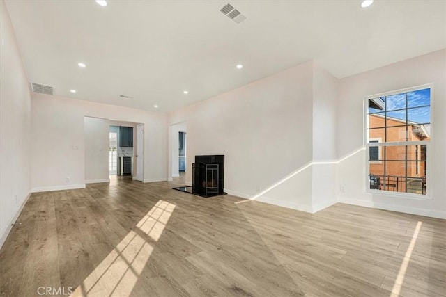 unfurnished living room with light wood-type flooring and a wood stove