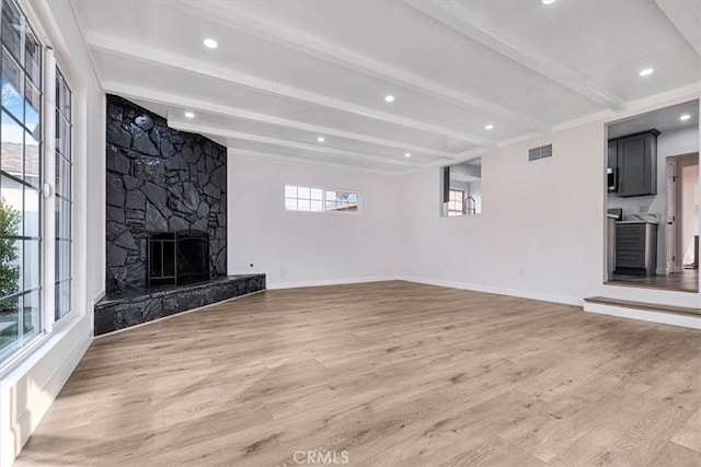 unfurnished living room featuring beam ceiling, a fireplace, and hardwood / wood-style flooring