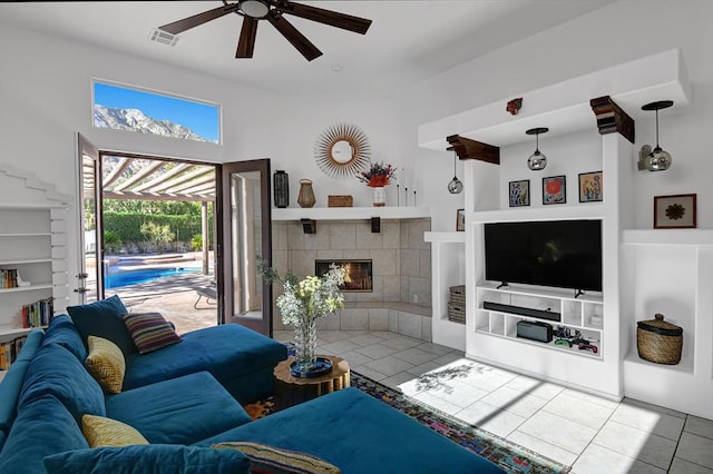 living room featuring ceiling fan, tile patterned flooring, built in shelves, and a fireplace