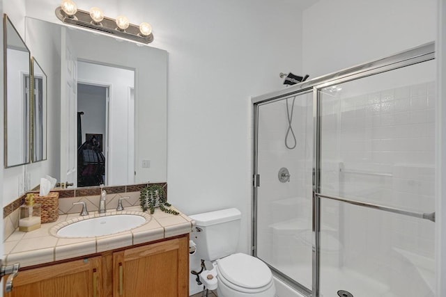 bathroom featuring toilet, a shower with door, and vanity