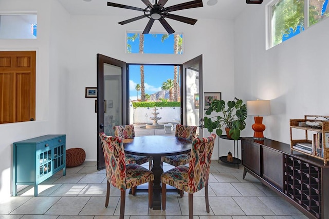 dining area with ceiling fan, light tile patterned floors, and a high ceiling