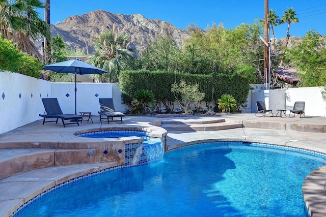 view of pool featuring a patio area, a mountain view, and an in ground hot tub