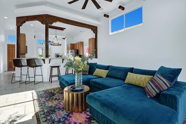 tiled living room with ceiling fan with notable chandelier