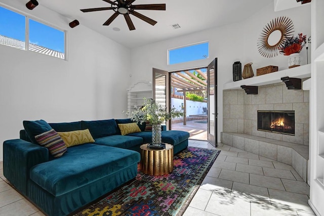 living room with ceiling fan, a wealth of natural light, light tile patterned floors, and a tiled fireplace