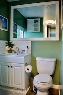 bathroom featuring toilet, decorative backsplash, and vanity