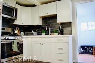 kitchen featuring tasteful backsplash, appliances with stainless steel finishes, and white cabinetry