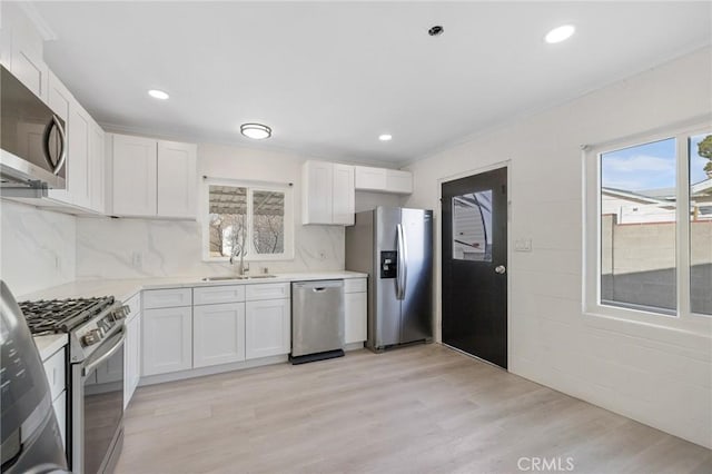 kitchen featuring decorative backsplash, sink, white cabinetry, and appliances with stainless steel finishes