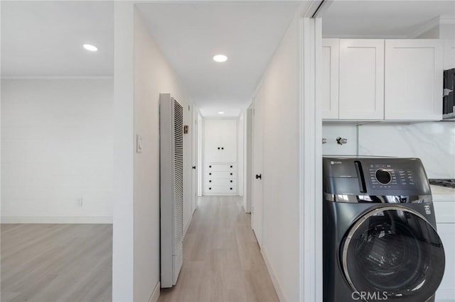 corridor with washer / clothes dryer, ornamental molding, and light hardwood / wood-style flooring