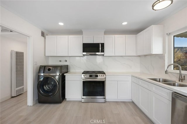 kitchen featuring white cabinets, washer / clothes dryer, appliances with stainless steel finishes, and sink