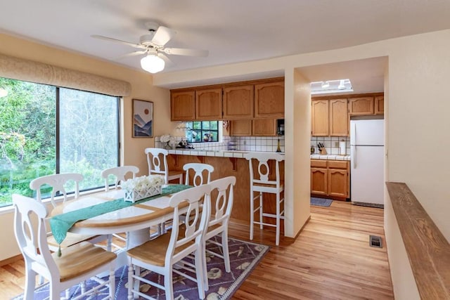 dining space featuring ceiling fan, a wealth of natural light, and light hardwood / wood-style floors