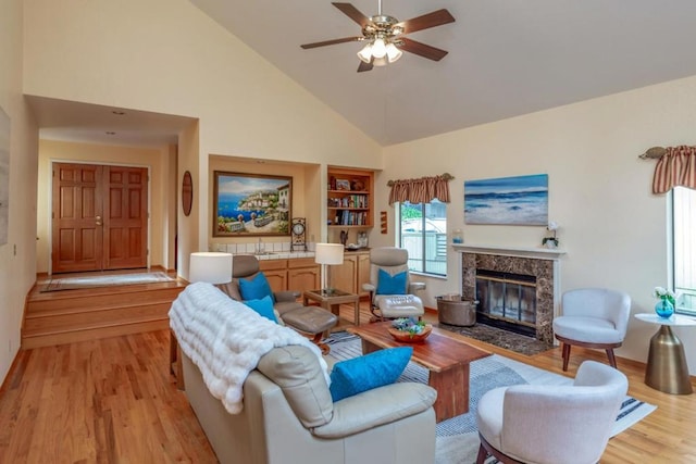 living room with ceiling fan, a premium fireplace, high vaulted ceiling, and light hardwood / wood-style flooring