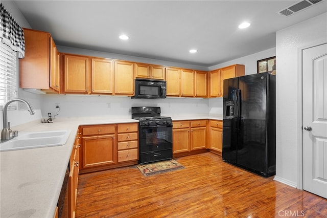 kitchen with black appliances, light wood-type flooring, and sink