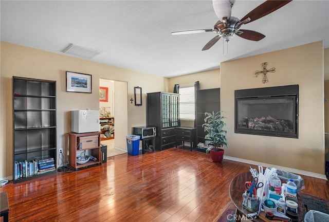 living room featuring ceiling fan, hardwood / wood-style floors, and a textured ceiling