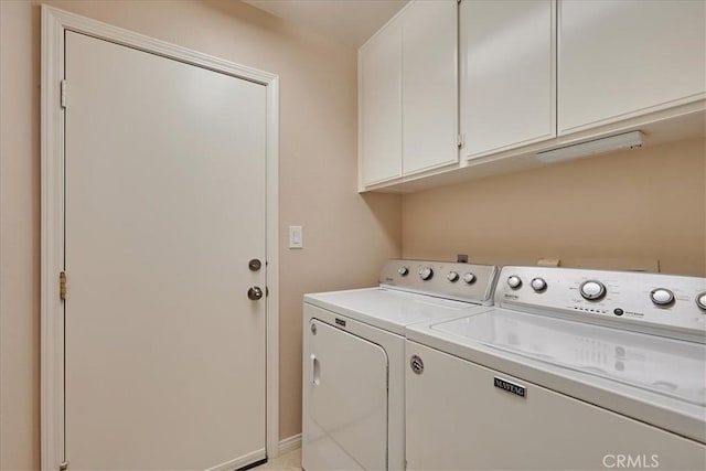 clothes washing area featuring cabinets and washer and clothes dryer